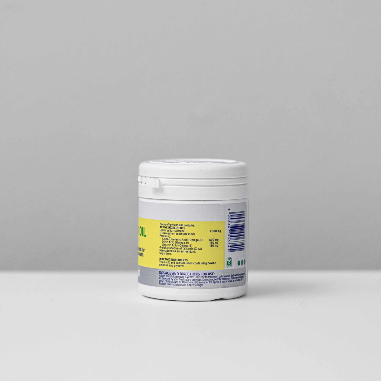 Container of Omega 3 6 and 9 Flax Seed Oil supplement capsules on plain background