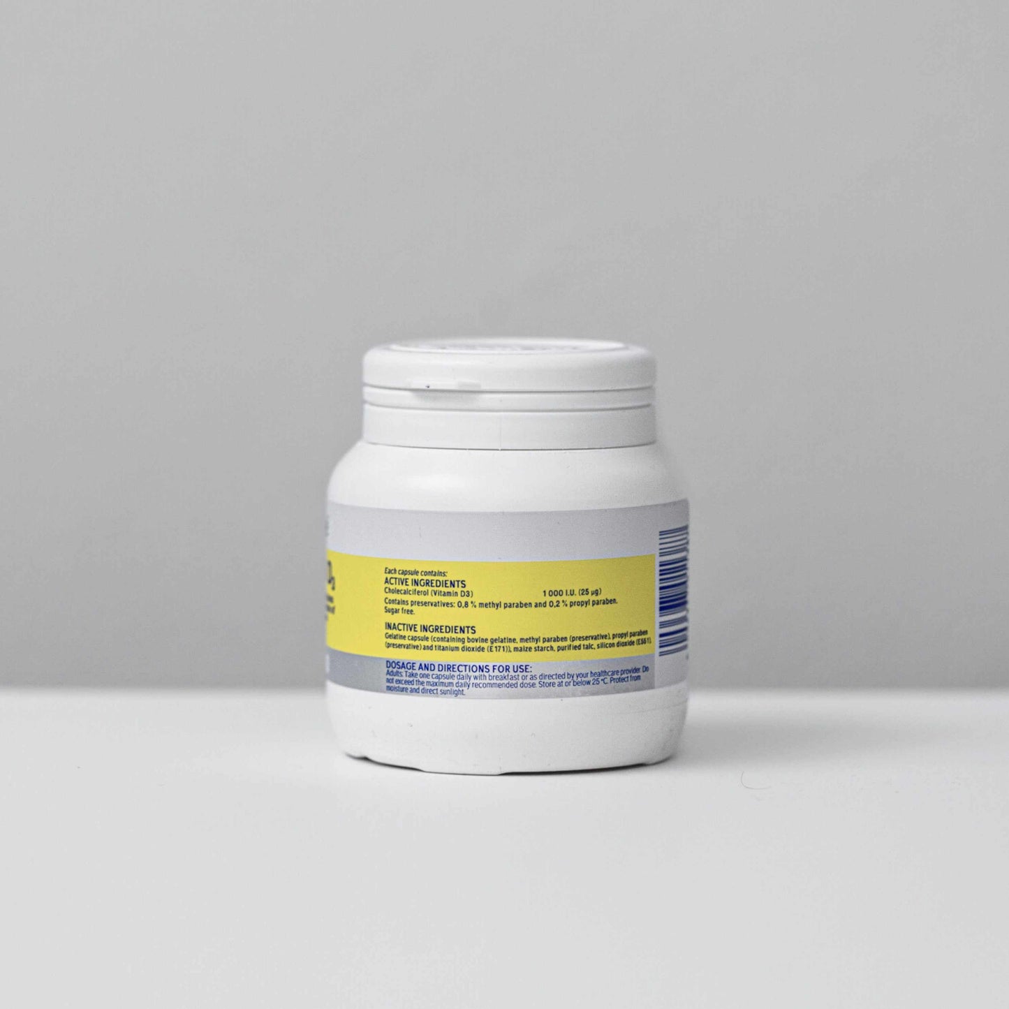 white bottle of Vitamin D capsules with yellow and gray label on a gray background