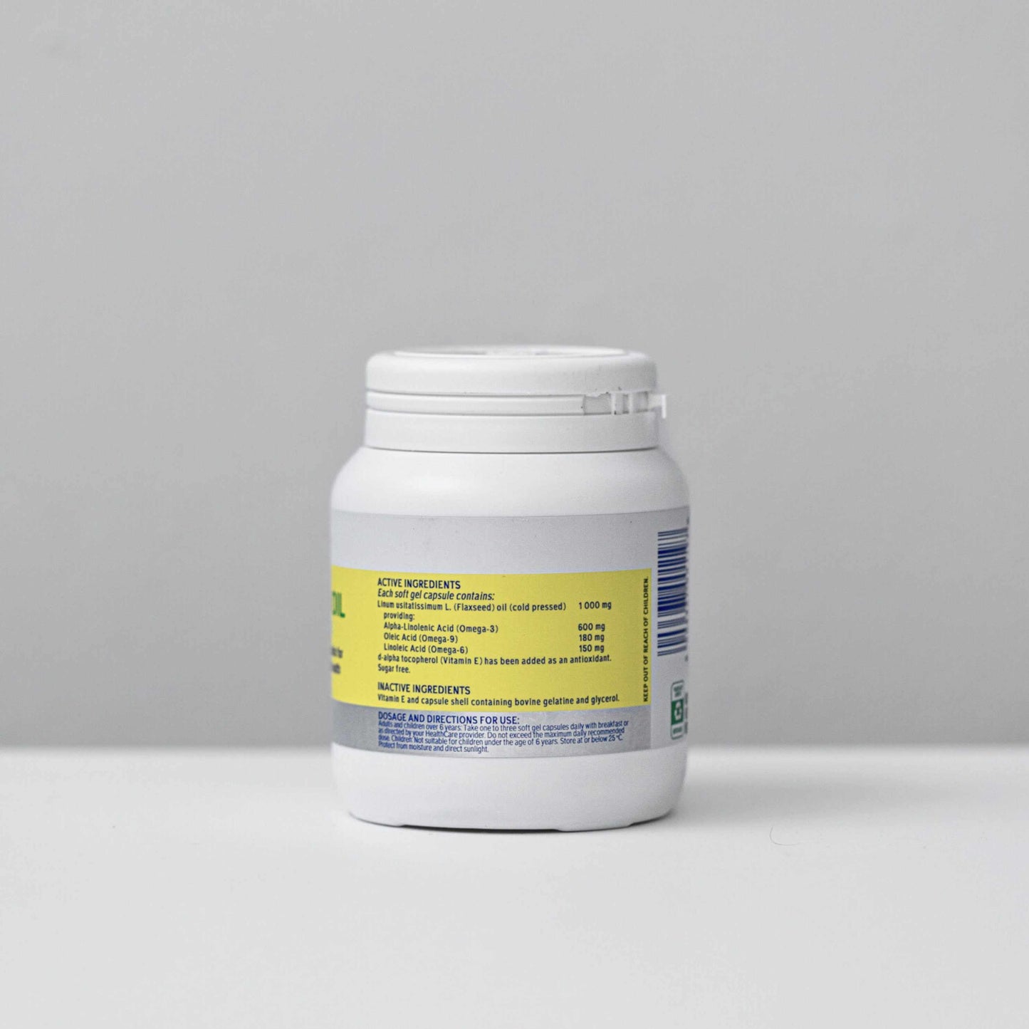 white bottle of Omega 3 6 and 9 flax seed oil capsules with yellow label against gray background