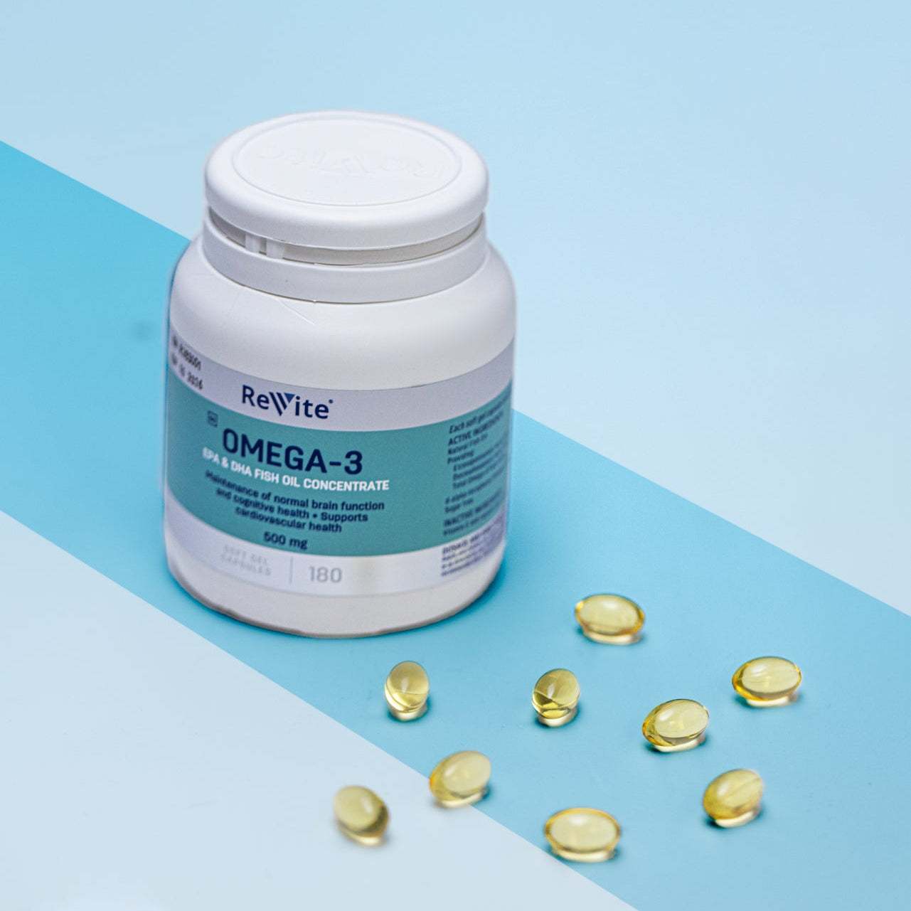 Bottle of Revite Omega 3 500mg capsules with scattered soft gels on blue background