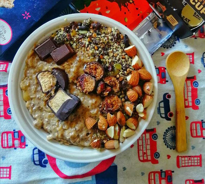 Bowl of Space Rocks oatmeal with almonds, chocolate, and seeds on colorful cloth with wooden spoon